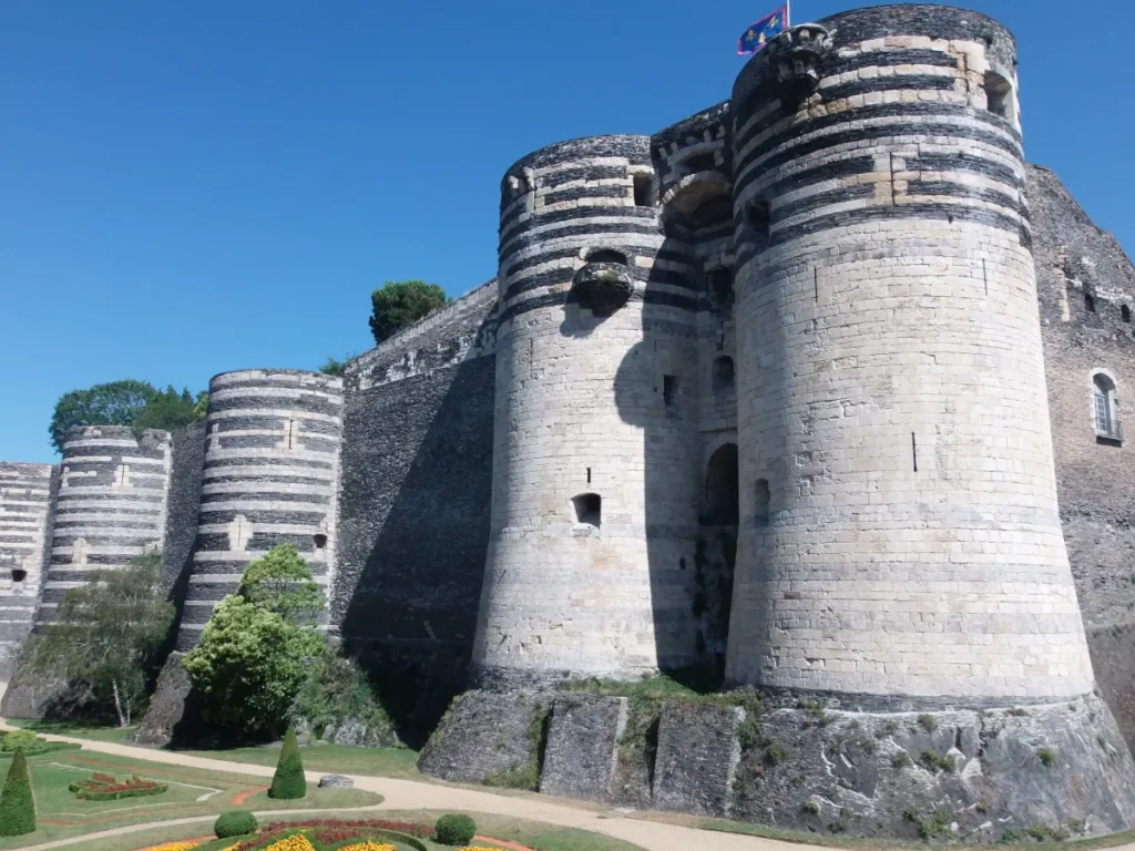 Tours rayées de schiste et de tuffeau du château d'Angers sous un ciel bleu