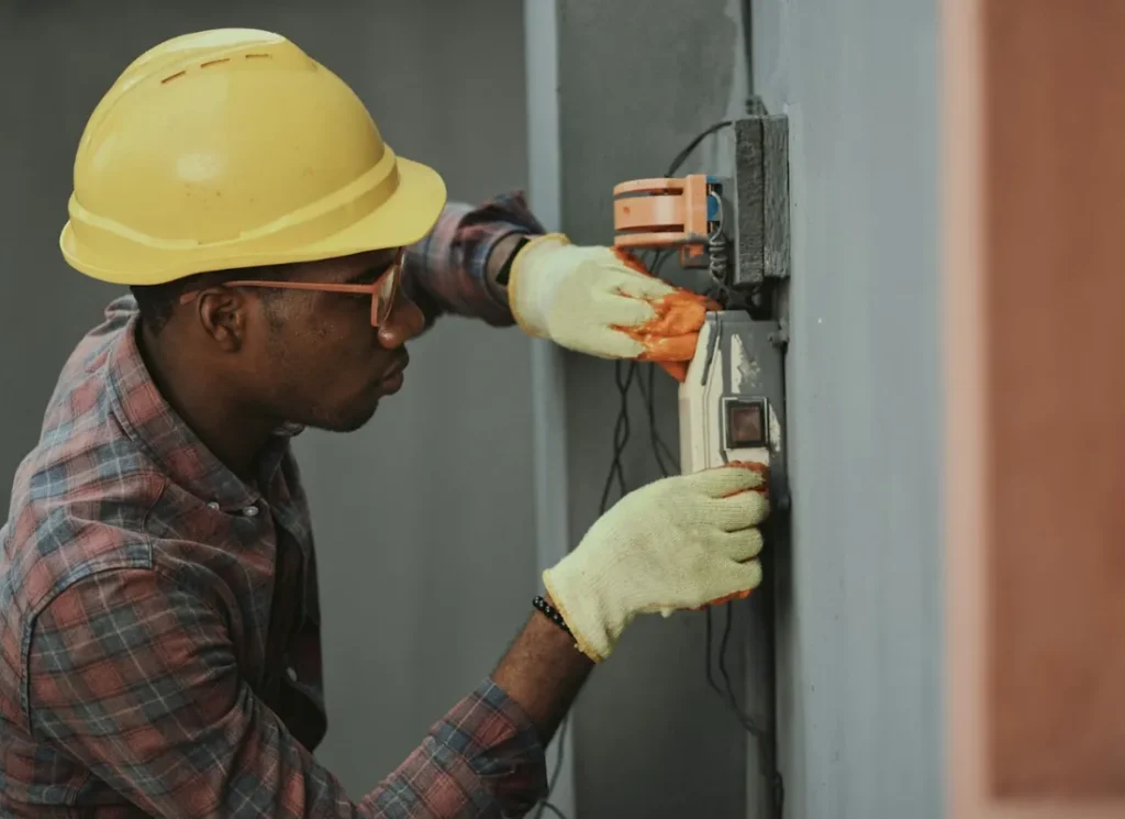 Électricien installant un tableau électrique avec casque de sécurité
