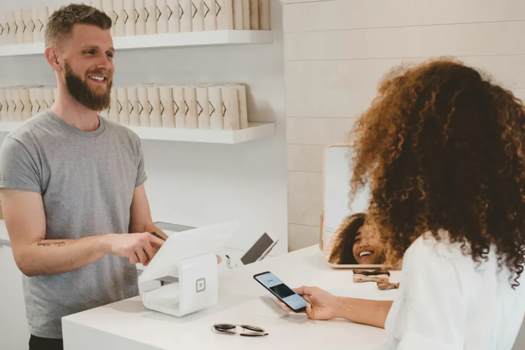 Commerçant encaissant une cliente au comptoir de sa boutique