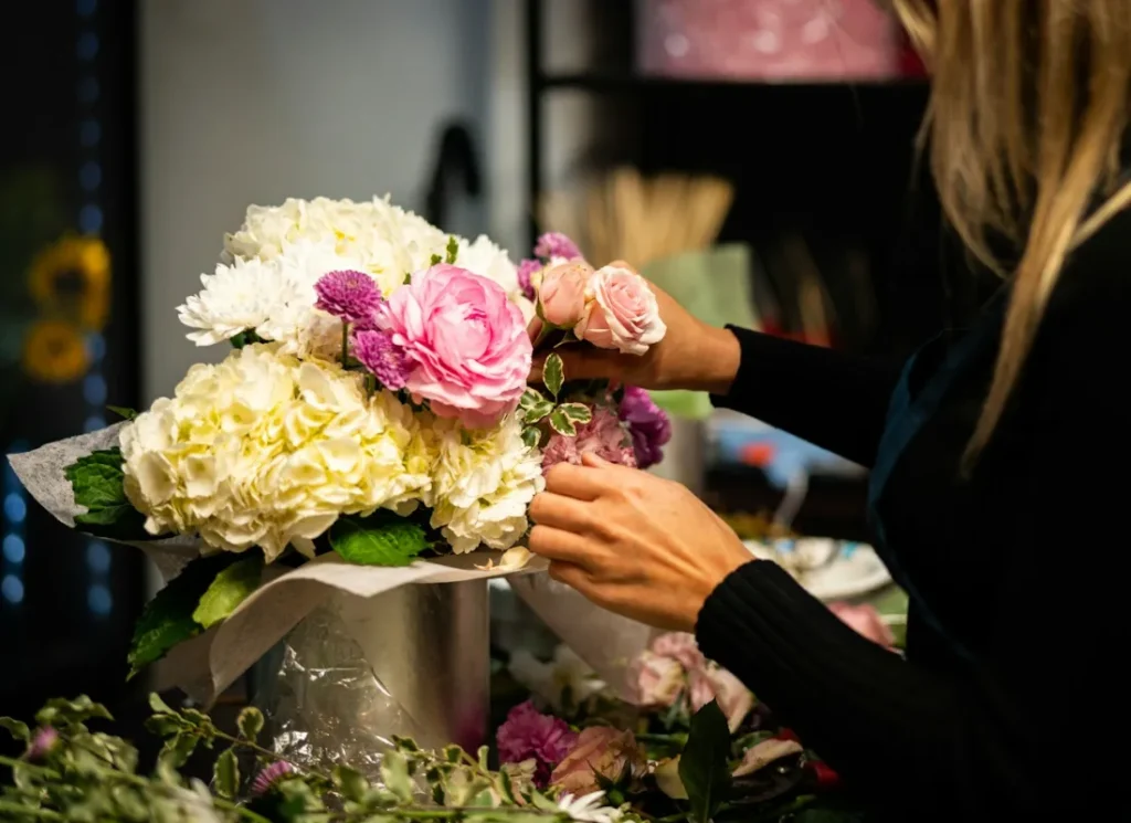 Fleuriste composant un bouquet dans sa boutique